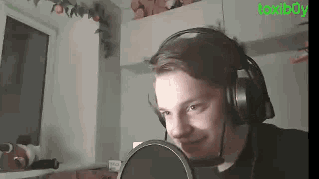 a young man wearing headphones and a microphone is smiling .