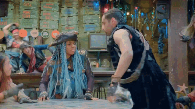 a woman with blue hair is sitting at a table with a man in a black vest