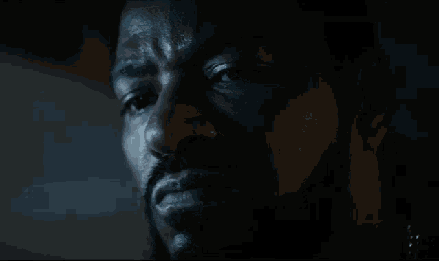 a close up of a man 's face with a beard in a dark room