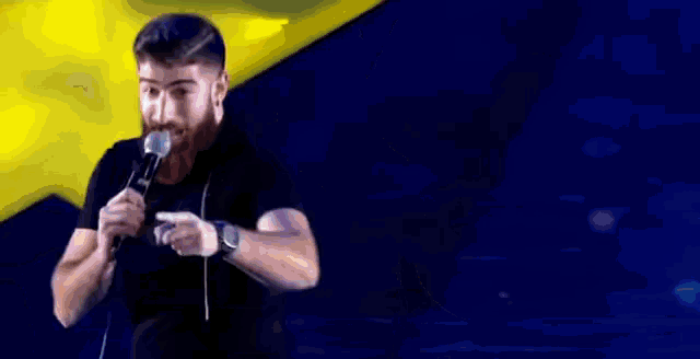 a man with a beard is holding a microphone in his mouth while standing on a stage .