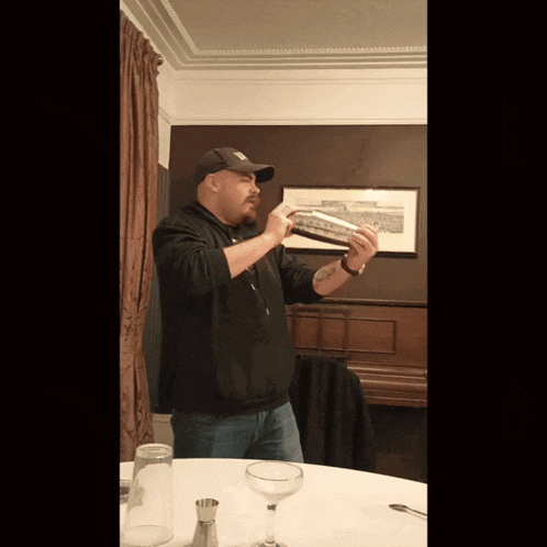 a man in a new york yankees hat is shaking a drink