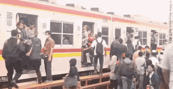 a crowd of people are boarding a train .