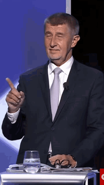 a man in a suit and tie is pointing at the camera