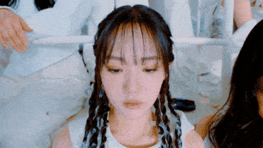 a girl with braids on her head looks down at something