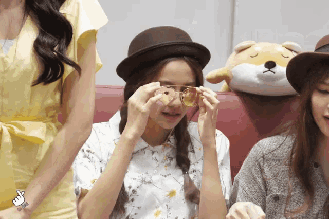 a woman wearing a hat and sunglasses has a finger up on her wrist