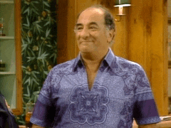 a man wearing a purple shirt is smiling in a living room