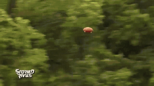 a football player is jumping in the air to catch a ball while another player tries to tackle him .
