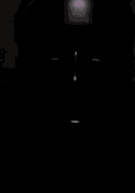 a person 's face is visible in the dark with a light shining on it .