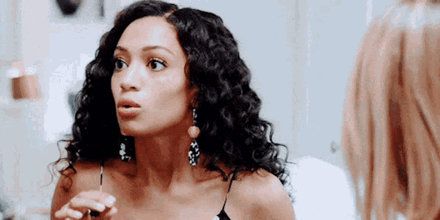 a woman with curly hair looks at herself in a mirror
