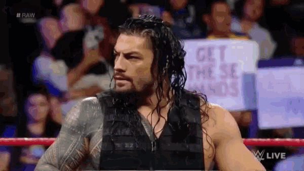 roman reigns is standing in a ring with a sign that says get these hands