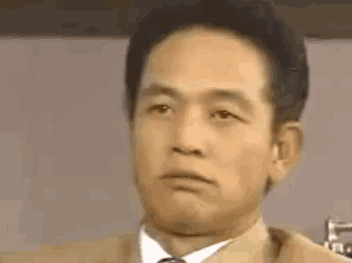 a close up of a man in a suit and tie making a face .