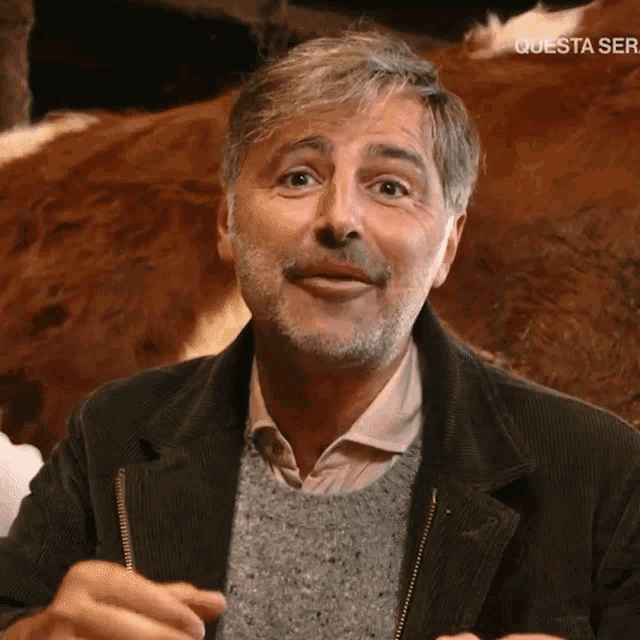 a man with a beard is standing in front of a cow and the words " questa ser " are visible