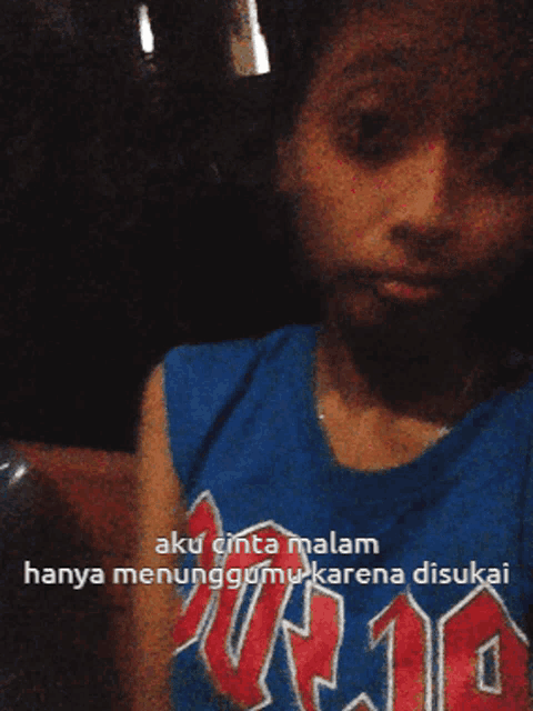 a person wearing a blue shirt that says ' aku cinta malam hanya menunggumu karena disukai ' on it