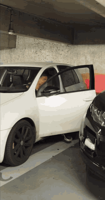 a white car is parked in a parking garage with the door open