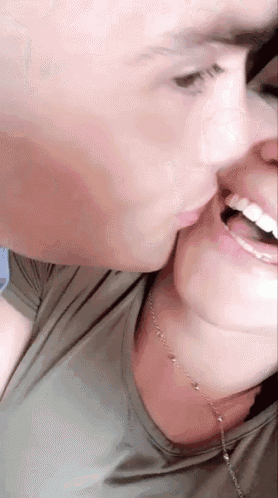 a man is kissing a woman on the cheek while the woman is smiling .
