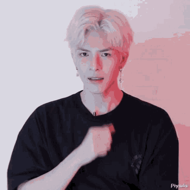 a man with white hair is wearing a black shirt and earrings .