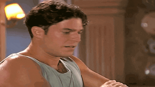 a man wearing a tank top is looking at something
