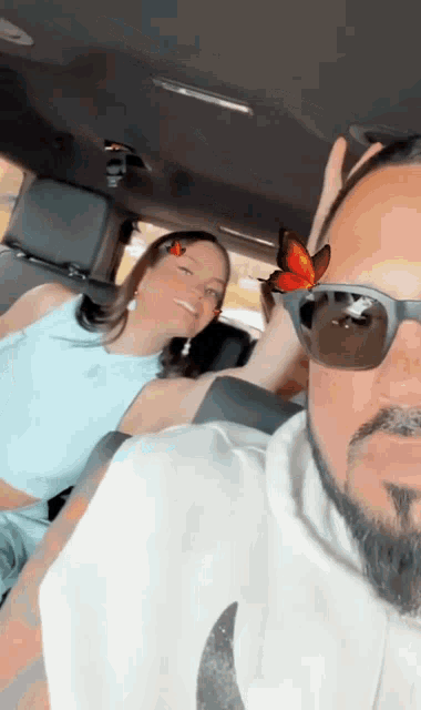 a man and a woman are sitting in a car with a butterfly on the woman 's head