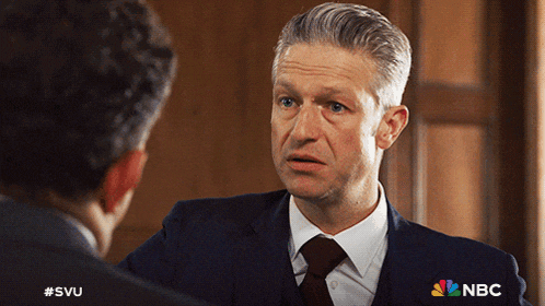 a man in a suit and tie is talking to another man with a nbc logo on his shirt