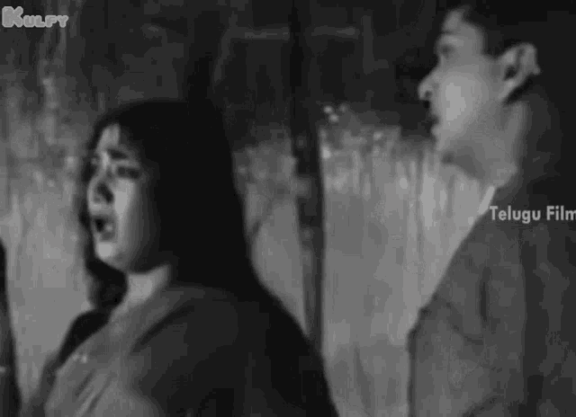 a man and a woman are standing next to each other in a black and white photo from a telugu film .