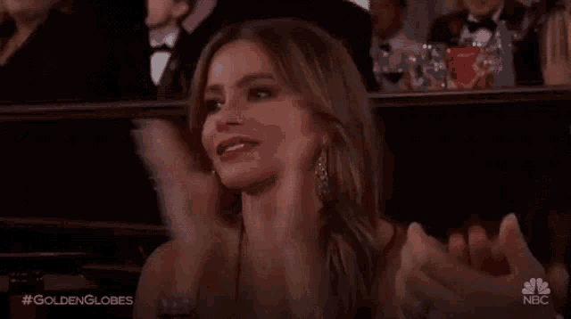 a woman is clapping her hands while sitting in a stadium .