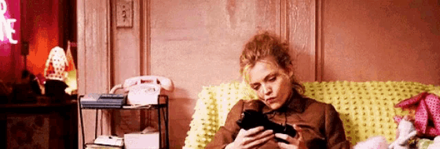a woman is sitting on a couch looking at her cell phone