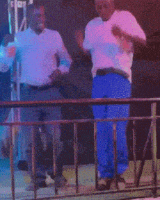 a man wearing sunglasses is standing next to another man wearing a white shirt