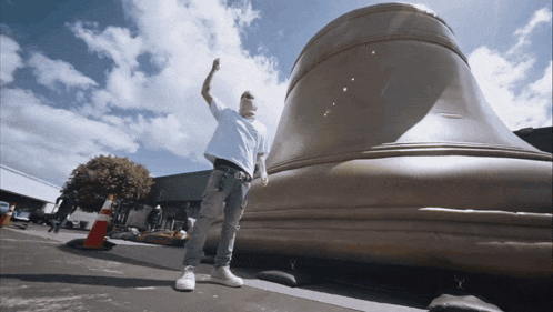 a man standing in front of a large bell with his hand in the air