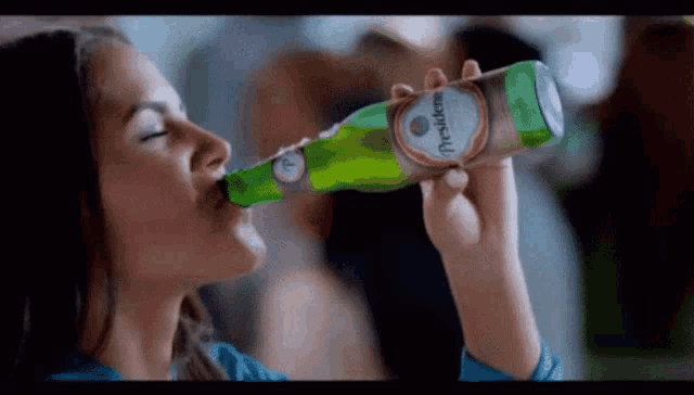 a woman drinking a bottle of presidente beer