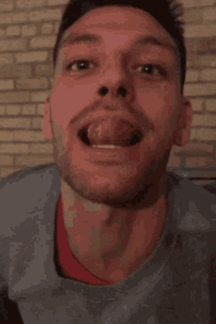 a man with his tongue out is wearing a gray shirt with the word brooklyn on it