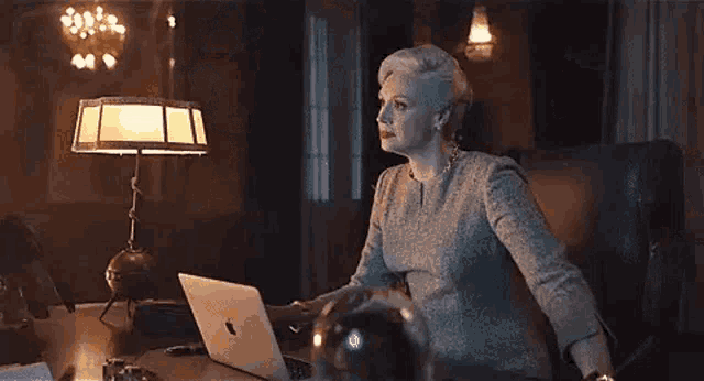 a woman is standing at a table with a lamp in a dark room .