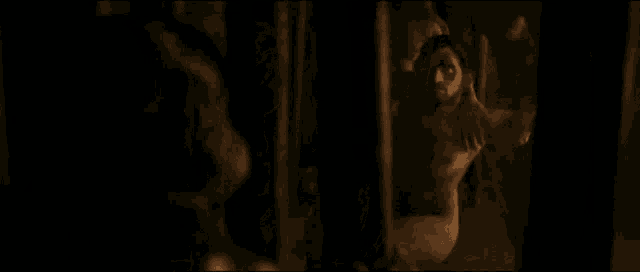a man with a beard and mustache is behind bars in a dark room