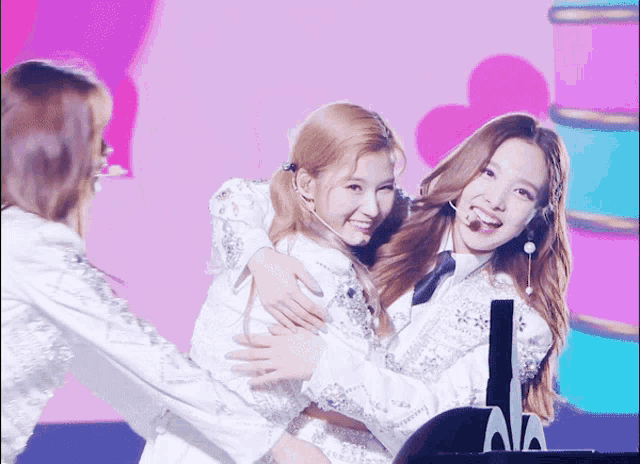 two girls are hugging each other and one has a microphone on