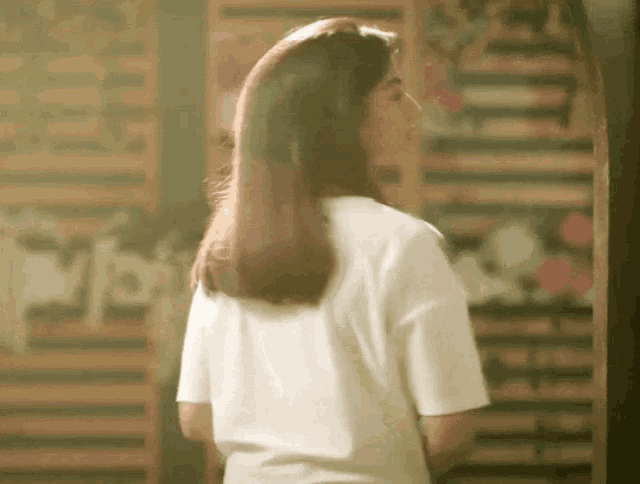 a woman in a white shirt is standing in front of a sign that says ' i love '