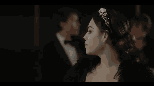 a woman wearing a tiara and a black dress is standing in front of a man in a suit .