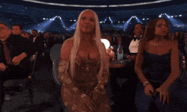 a woman with blonde hair is sitting in a stadium with other people