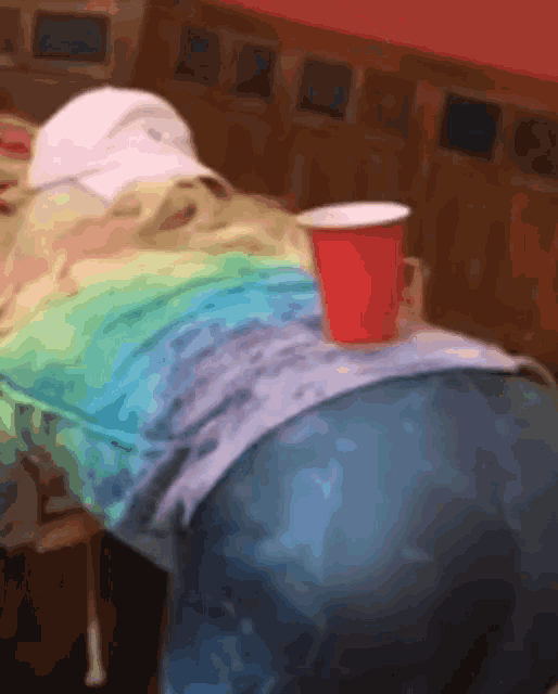 a red cup sits on a table next to a person 's butt