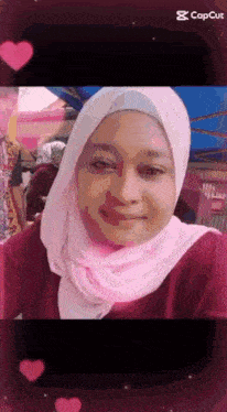 a woman wearing a pink hijab and a red shirt is smiling for the camera