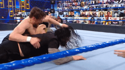 two men are wrestling in a wrestling ring with a crowd watching behind them