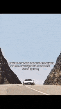 a car is driving down a road between two mountains .