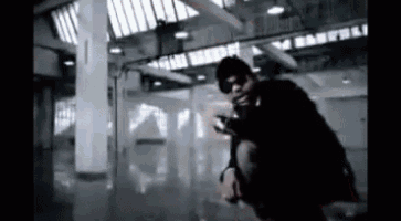 a man is kneeling down in a dark room with a gun .