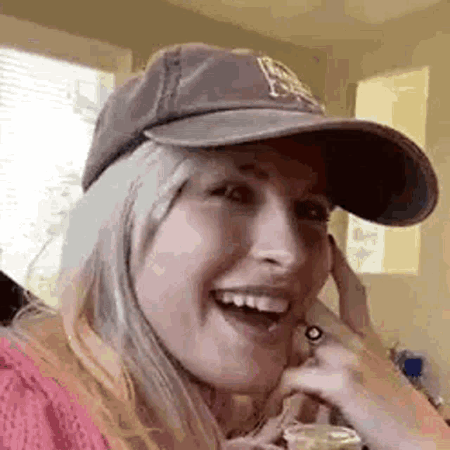 a woman wearing a hat and a ring is laughing .