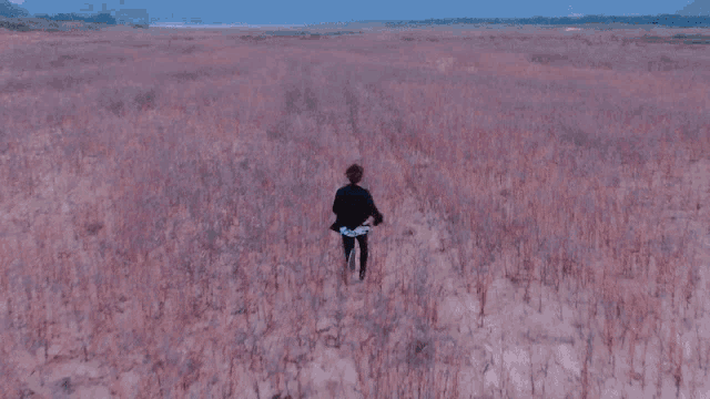 a group of young men are running through a field of tall grass .