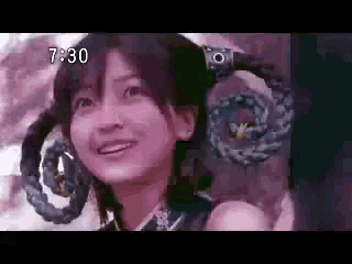 a close up of a woman 's face with a snake in the background and the time 7:30 .