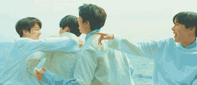 a group of young men wearing white shirts are standing next to each other on a beach .