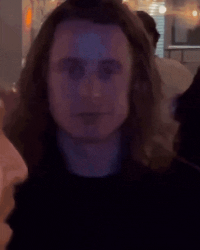 a man with long hair is looking at the camera in a blurry photo