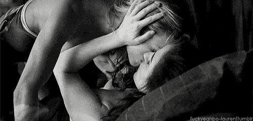 a man and a woman are laying on a bed and kissing .