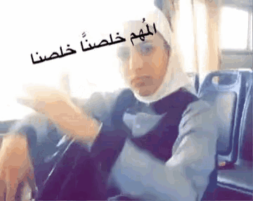 a woman wearing a hijab is sitting on a bus with her hands outstretched .