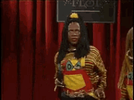 a man with dreadlocks is standing in front of a red curtain holding a microphone ..
