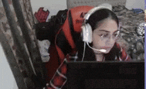 a woman wearing headphones and glasses is sitting in front of a computer monitor .